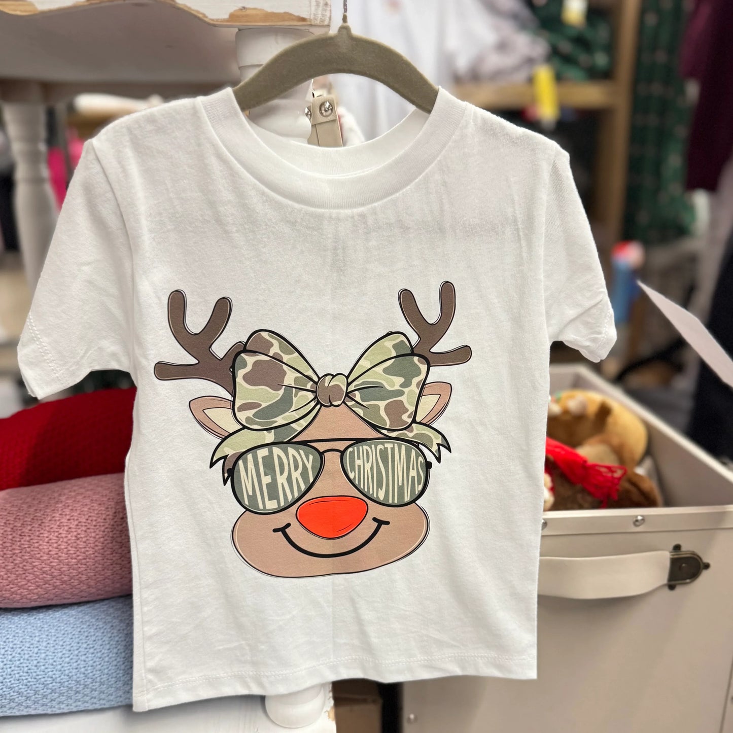 White t-shirt with reindeer design and 'Merry Christmas' text on a hanger.