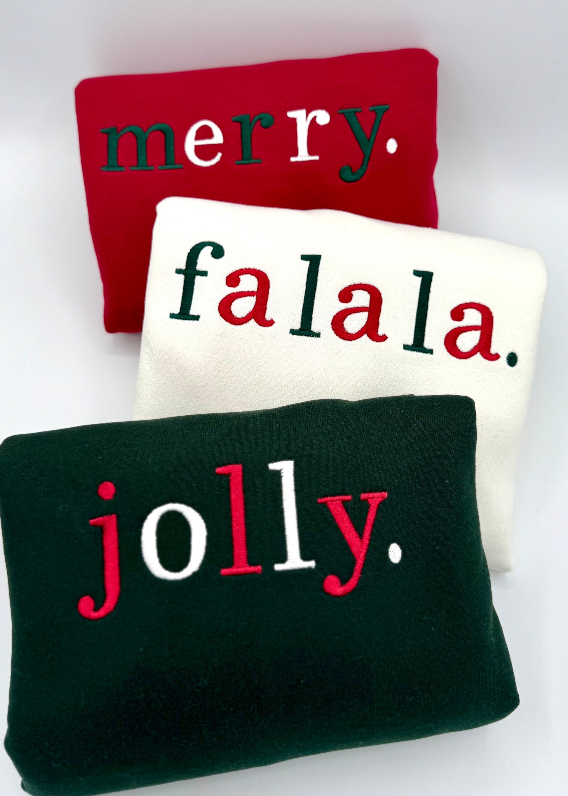 Three sweatshirts with Christmas-themed text on a white background