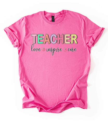 Pink t-shirt with 'TEACHER love inspire care' text on a white background