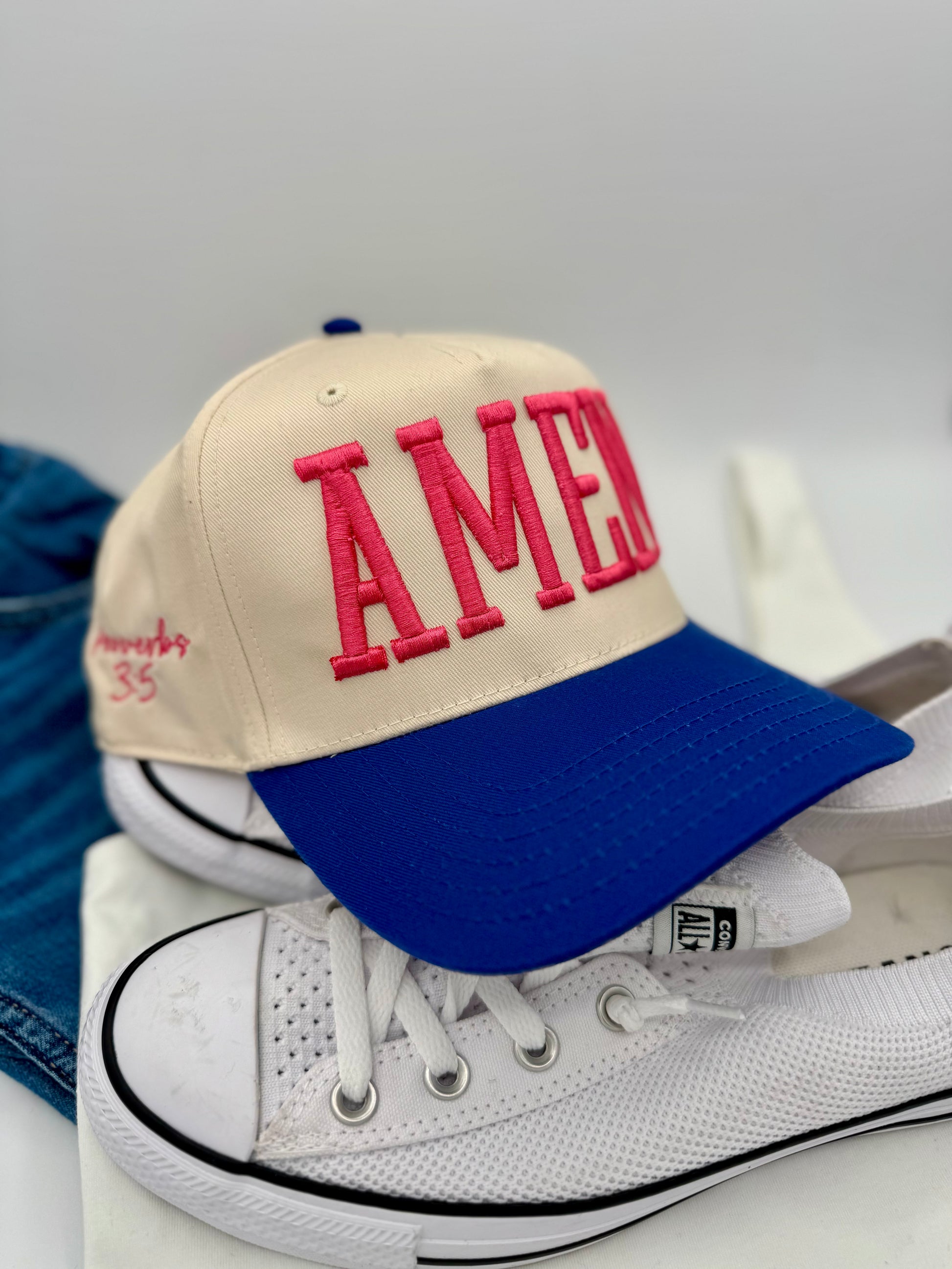 Cap with 'AMER' on a white sneaker against a gray background