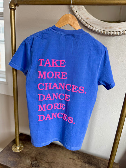 Blue t-shirt with pink text on a hanger against a neutral wall. Dancer quote shirt.