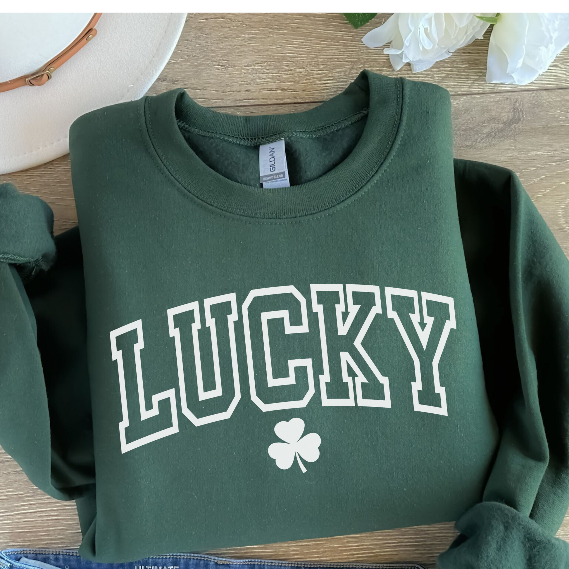 Green sweatshirt with 'LUCKY' and a shamrock on a wooden surface