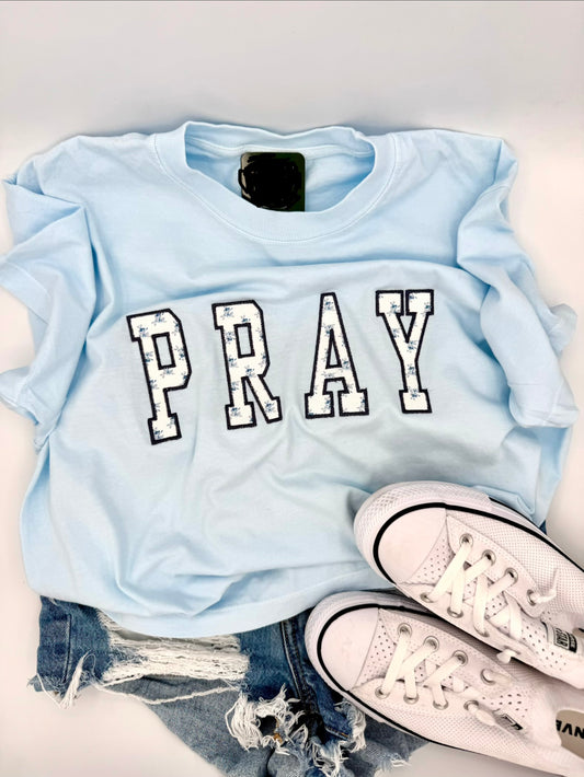 Blue boxy tshirt with the word pray embroidered across the front 