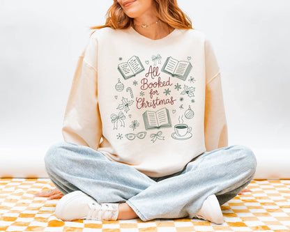 Person wearing a white sweatshirt with 'All Booked for Christmas' design sitting on a checkered floor.