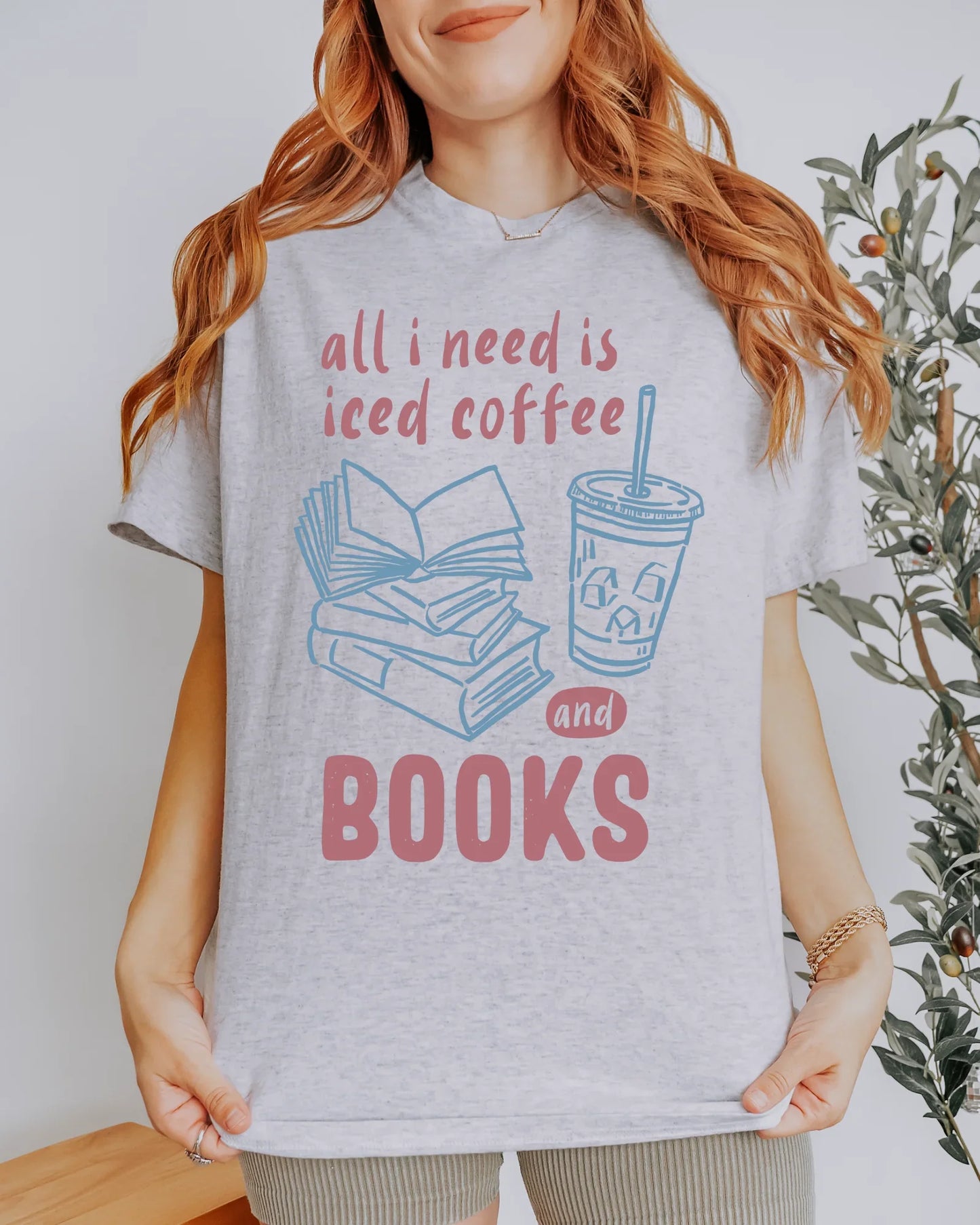 Person wearing a t-shirt with 'all I need is iced coffee and books' design.