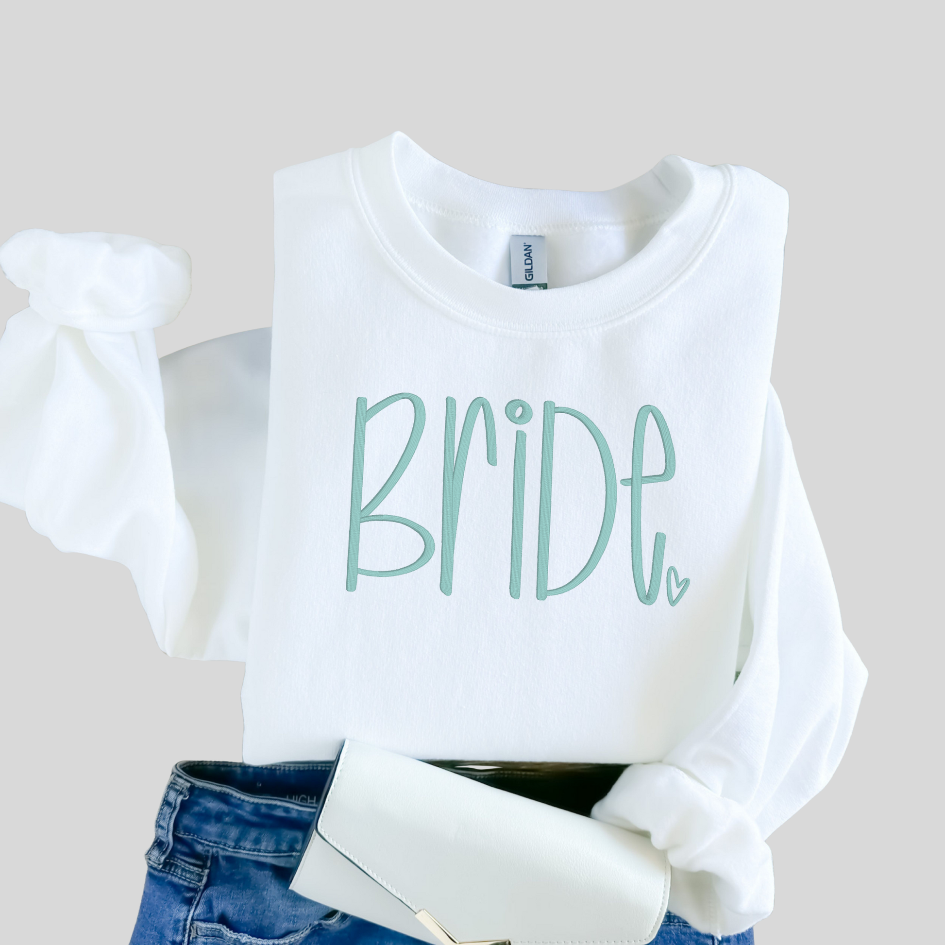 White sweatshirt with 'BRIDE' text on a neutral background