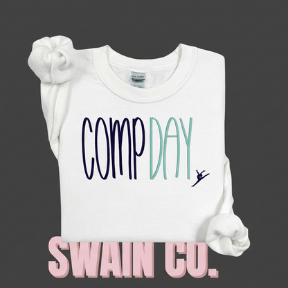 White sweatshirt with 'COMP DAY' and a dancer graphic embroidered on a light pink background