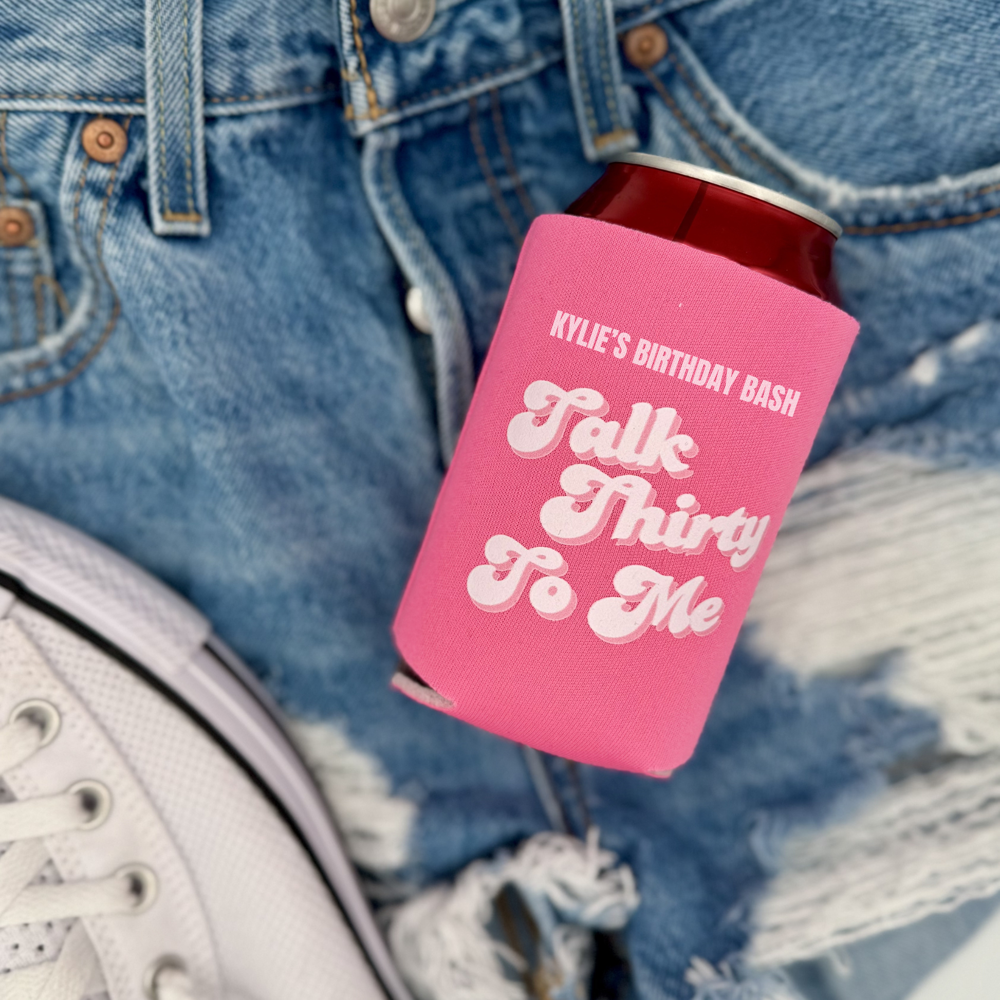 Pink can cooler with text on a denim background