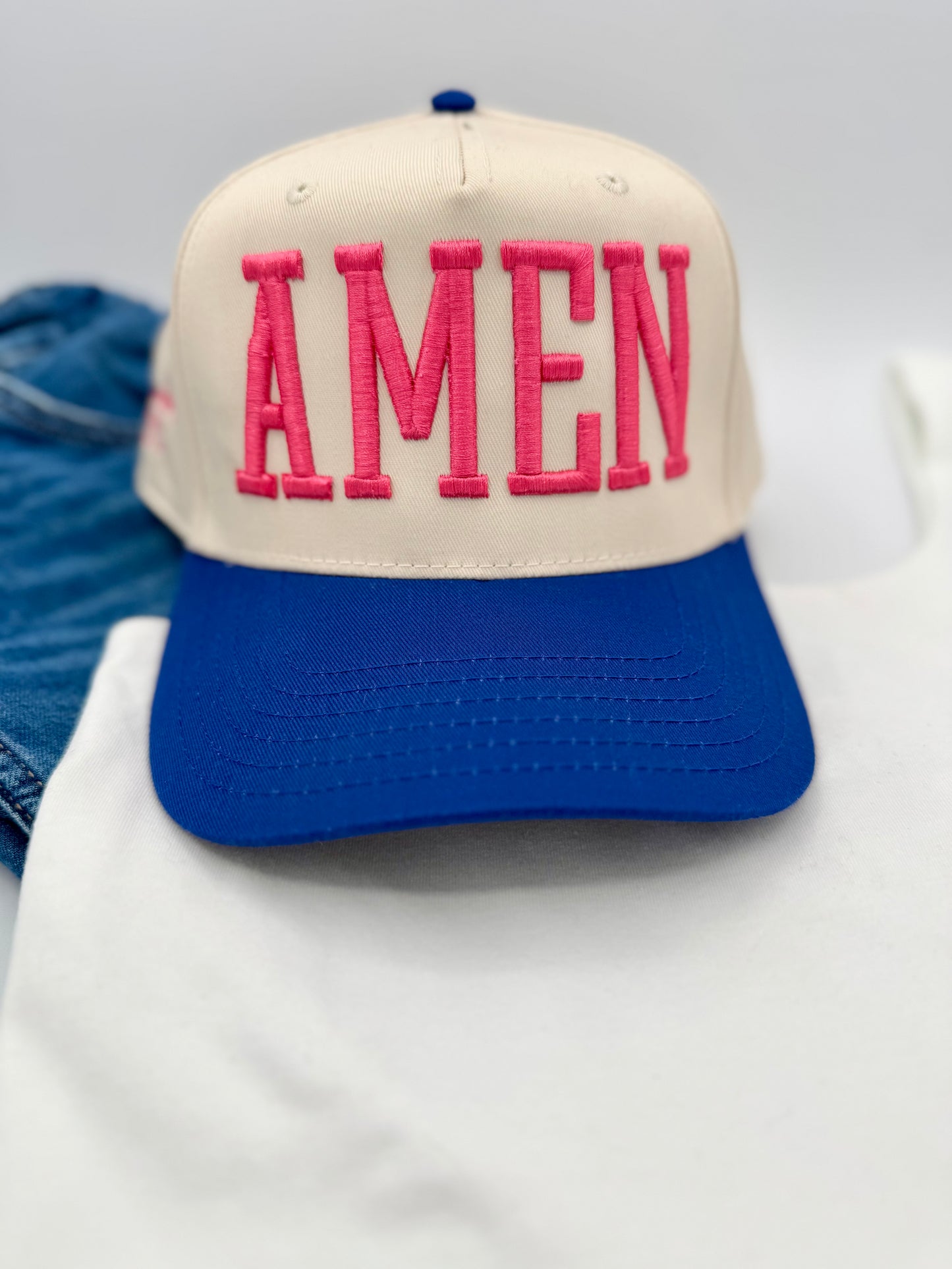 Cap with 'AMEN' in pink on a blue and beige background
