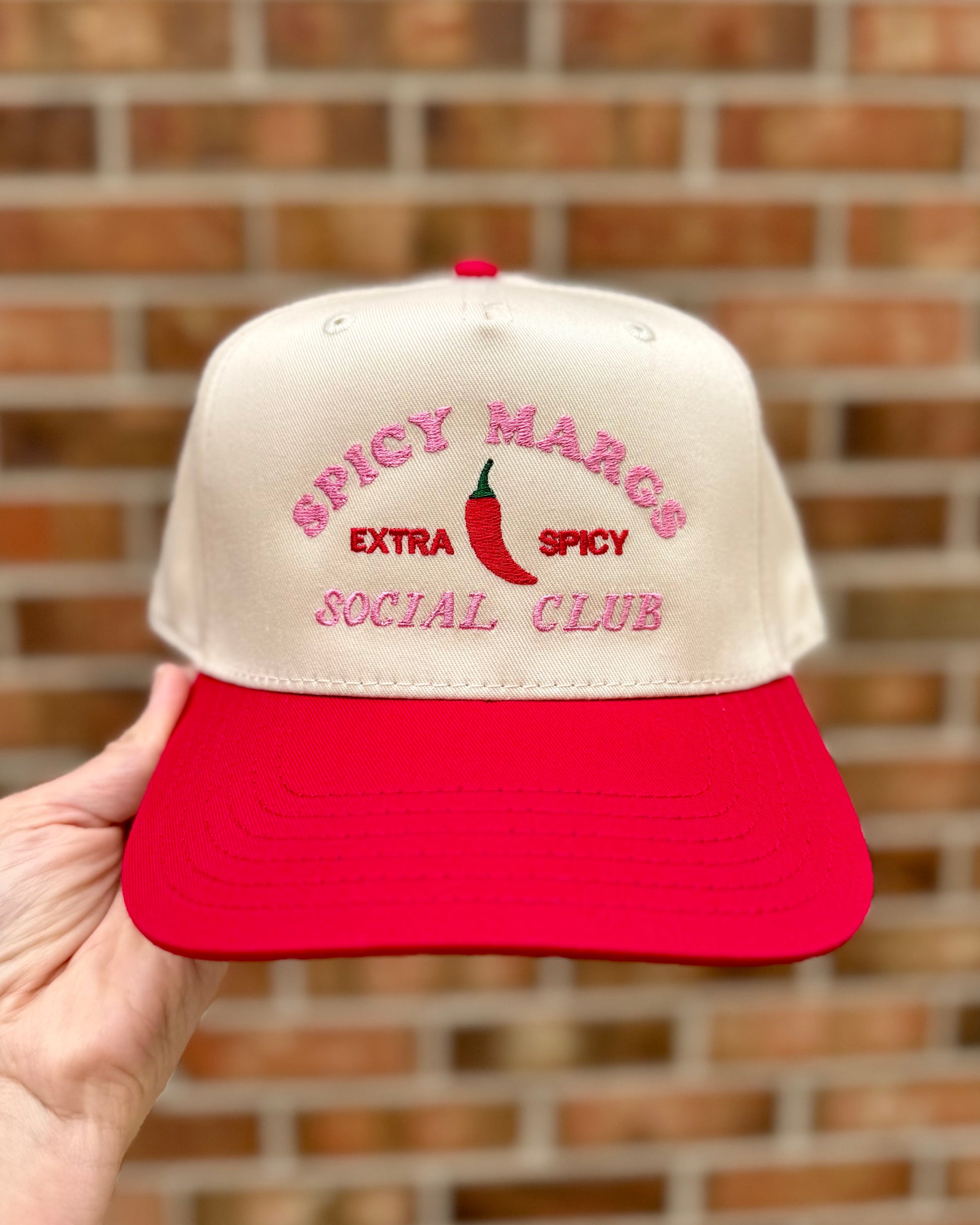 Cap with 'Spicy Margs Extra Spicy Social Club' text and red chili pepper design against a brick wall.