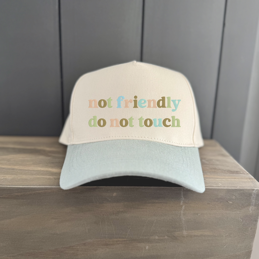 Cap with 'not friendly do not touch' text on a wooden surface and gray background