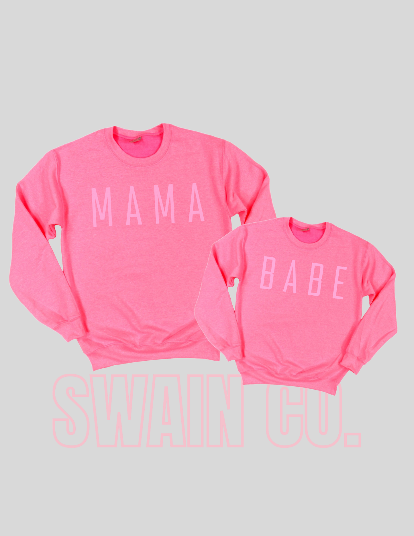 Two pink sweatshirts with 'MAMA' and 'BABE' text on a light gray background.