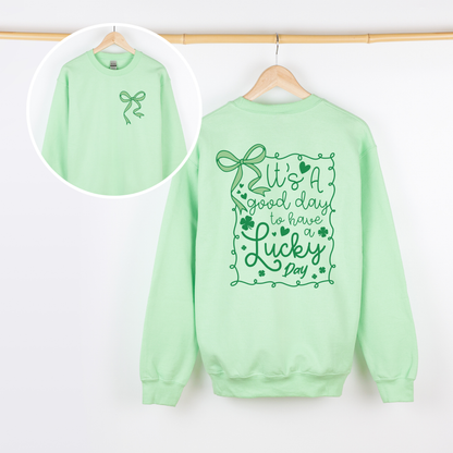 Light green sweatshirt with decorative text and graphics on a white background. Says its a good day to have a lucky day. 