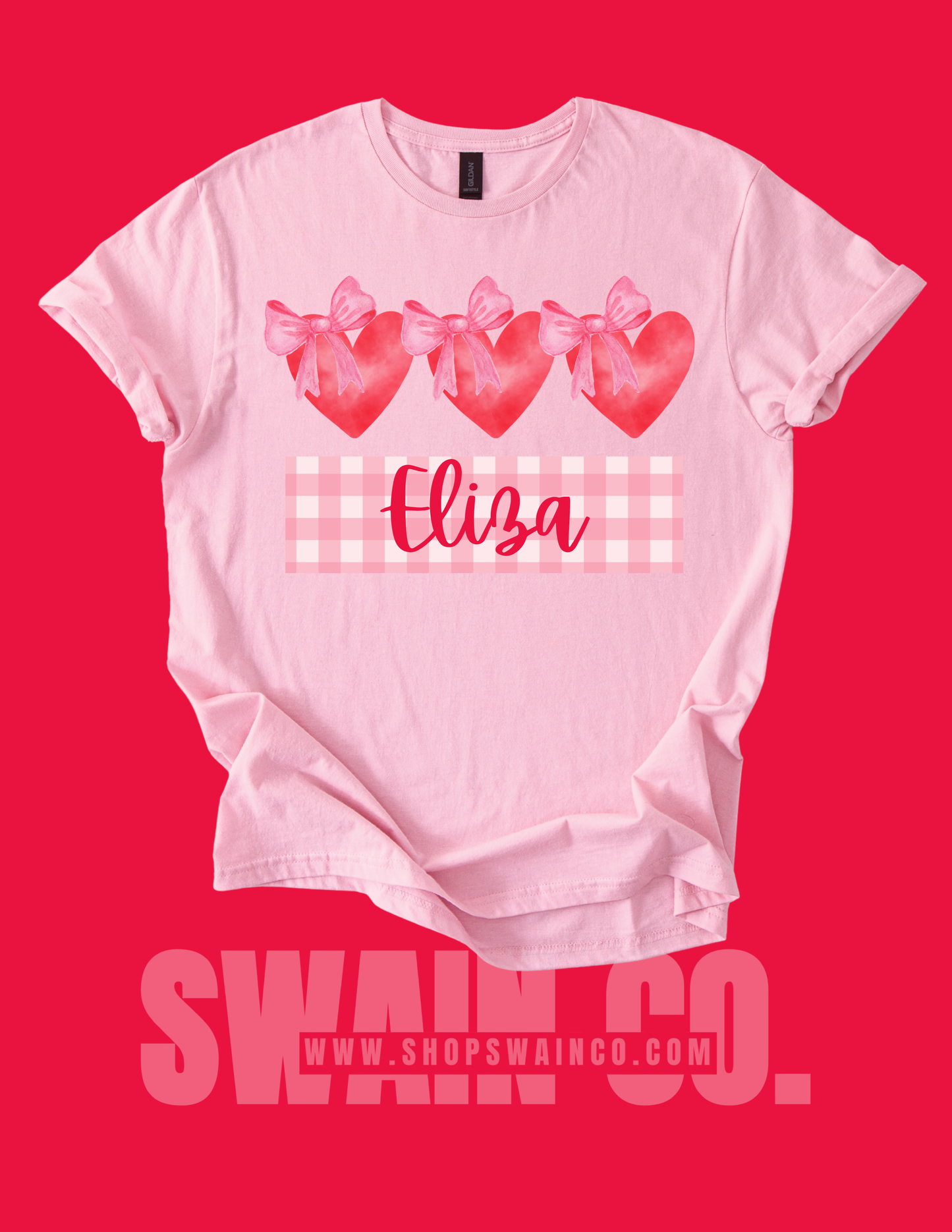 Pink t-shirt with heart designs and the name 'Eliza' on a red background, featuring the brand 'SWAAN CO.'
