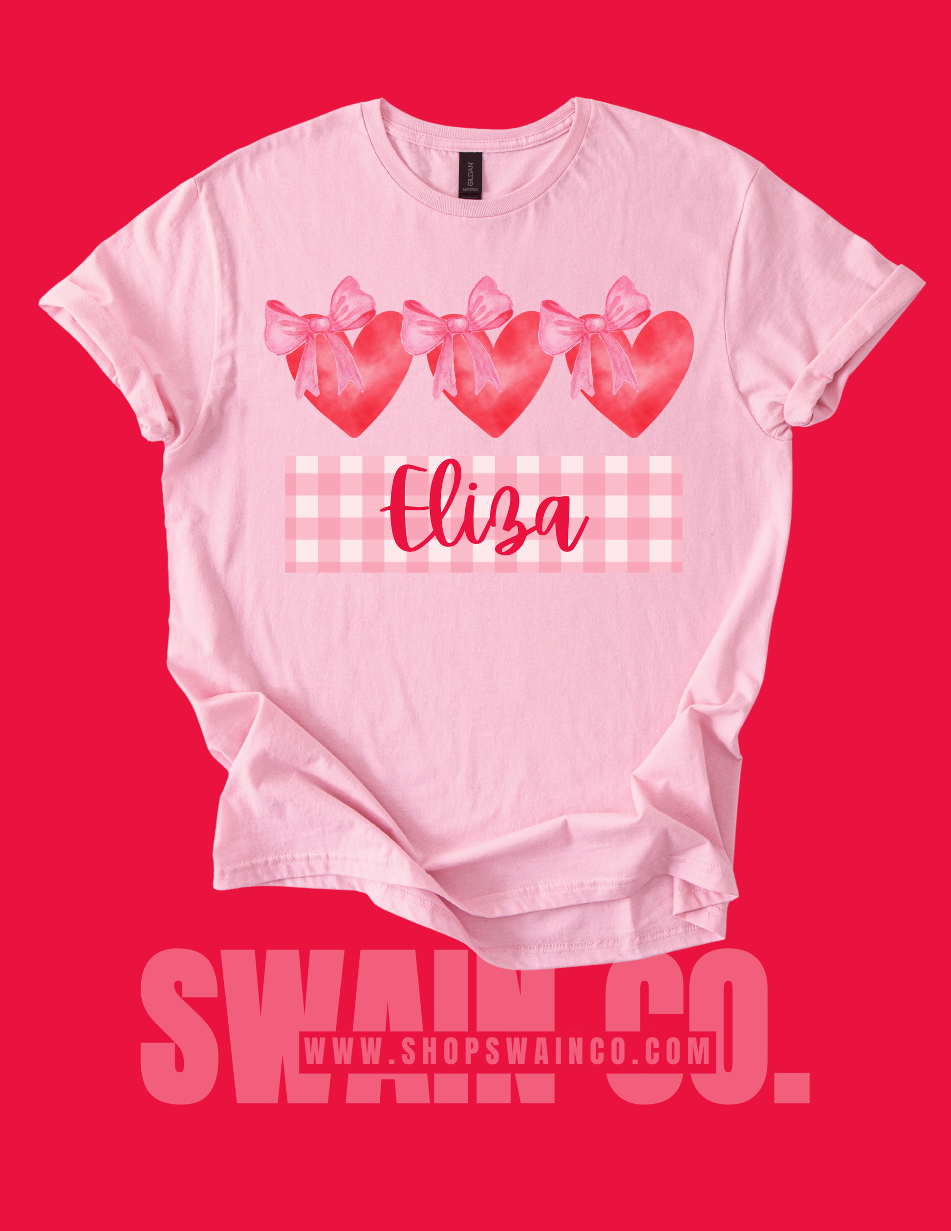 Pink t-shirt with heart designs and the name 'Eliza' on a red background, featuring the brand 'SWAAN CO.'