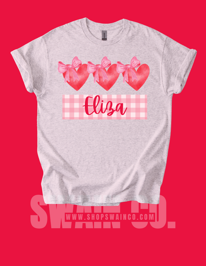 Gray t-shirt with pink hearts and bows on a red background