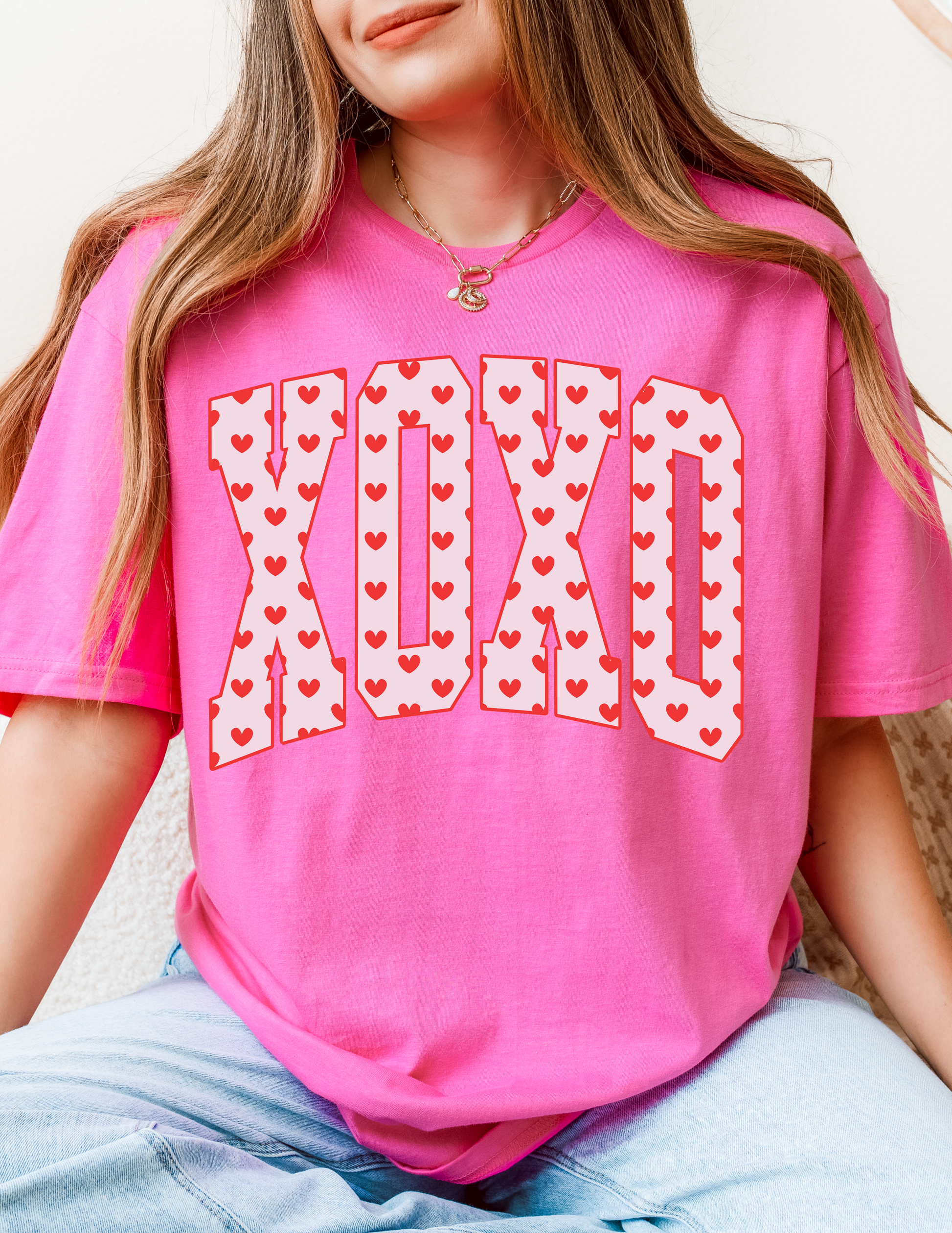 Person wearing a pink t-shirt with 'XOXO' design