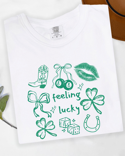 White t-shirt with green graphics and text on a white background. Tshirt says feeling lucky