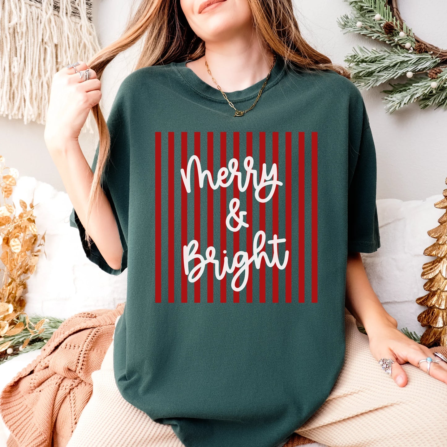 Comfort Colors Merry & Bright Striped T-Shirt in red and green with minimalistic modern holiday design, displayed folded on neutral background — Christmas graphic tee with festive striped lettering.