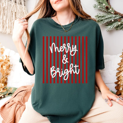 Comfort Colors Merry & Bright Striped T-Shirt in red and green with minimalistic modern holiday design, displayed folded on neutral background — Christmas graphic tee with festive striped lettering.