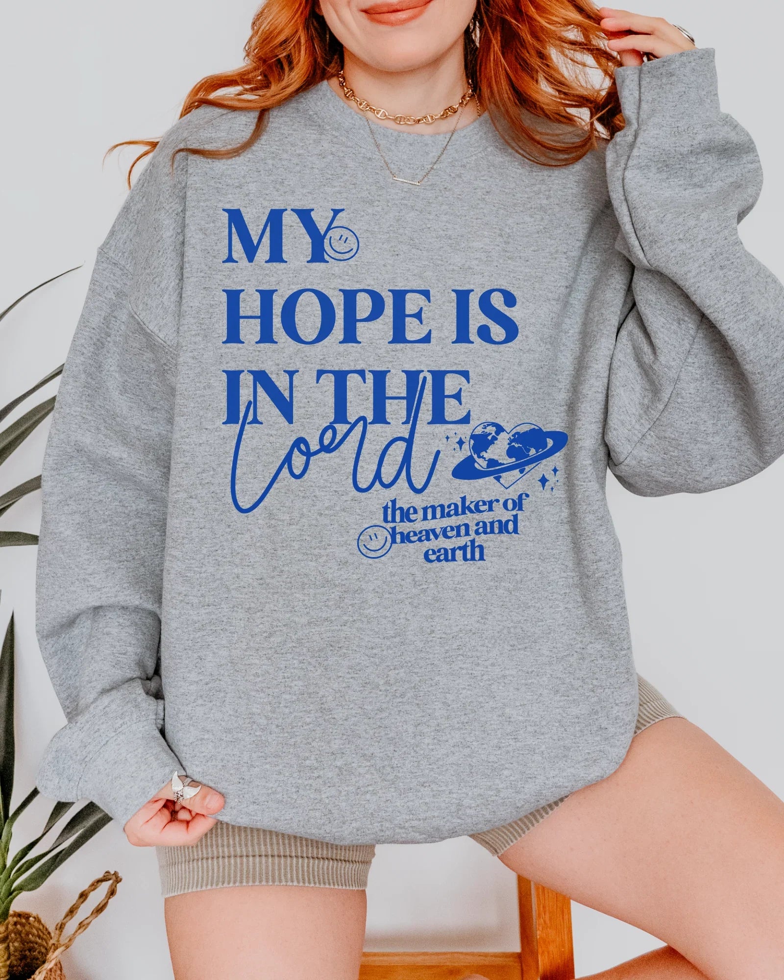 Person wearing a gray hoodie with blue text and design. Christian apparel