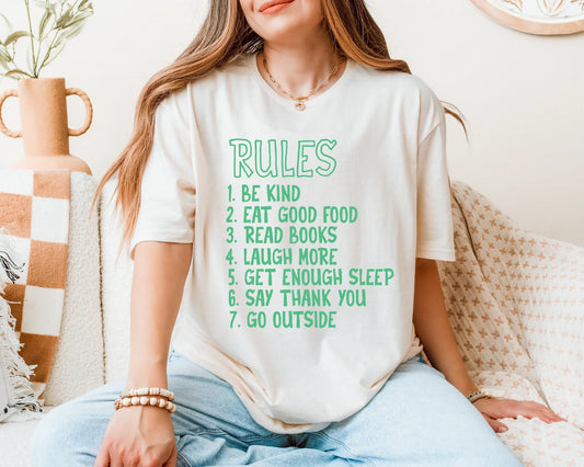 Person wearing a white t-shirt with green text rules on a cozy indoor setting