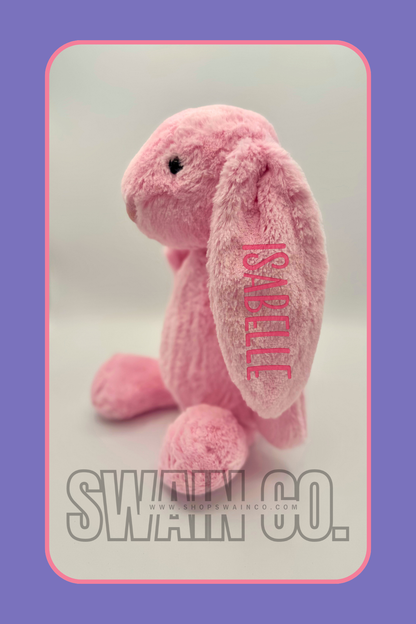 Pink plush toy with 'Korali' branding on a light gray background