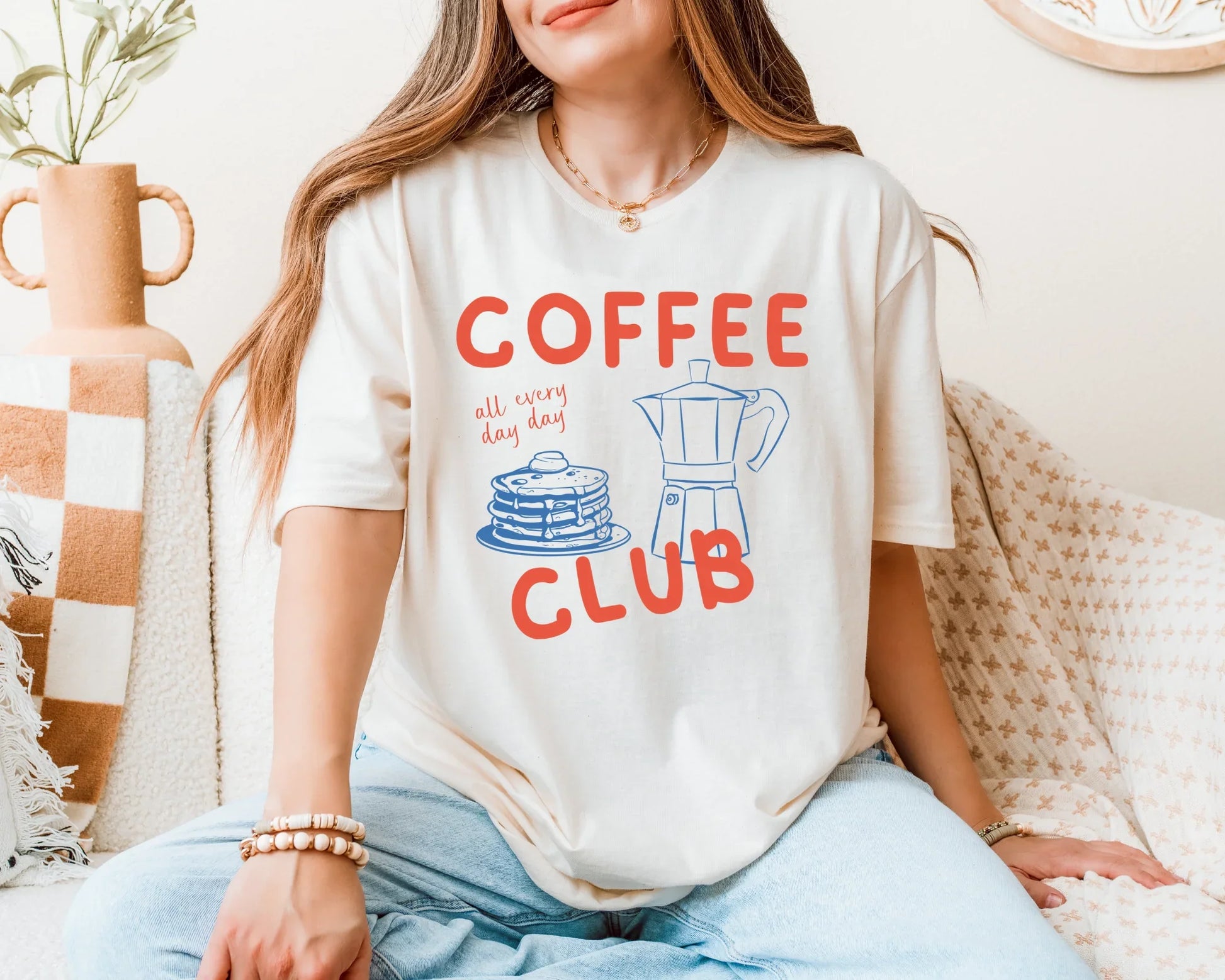 Person wearing a 'Coffee Club' t-shirt sitting on a couch.