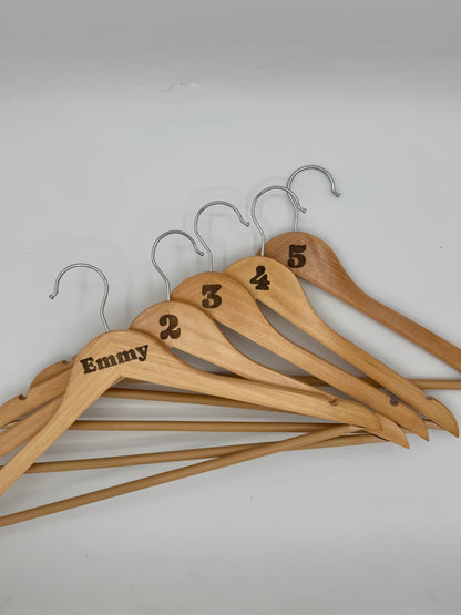 Set of wooden hangers with numbered and personalized labels on a white background